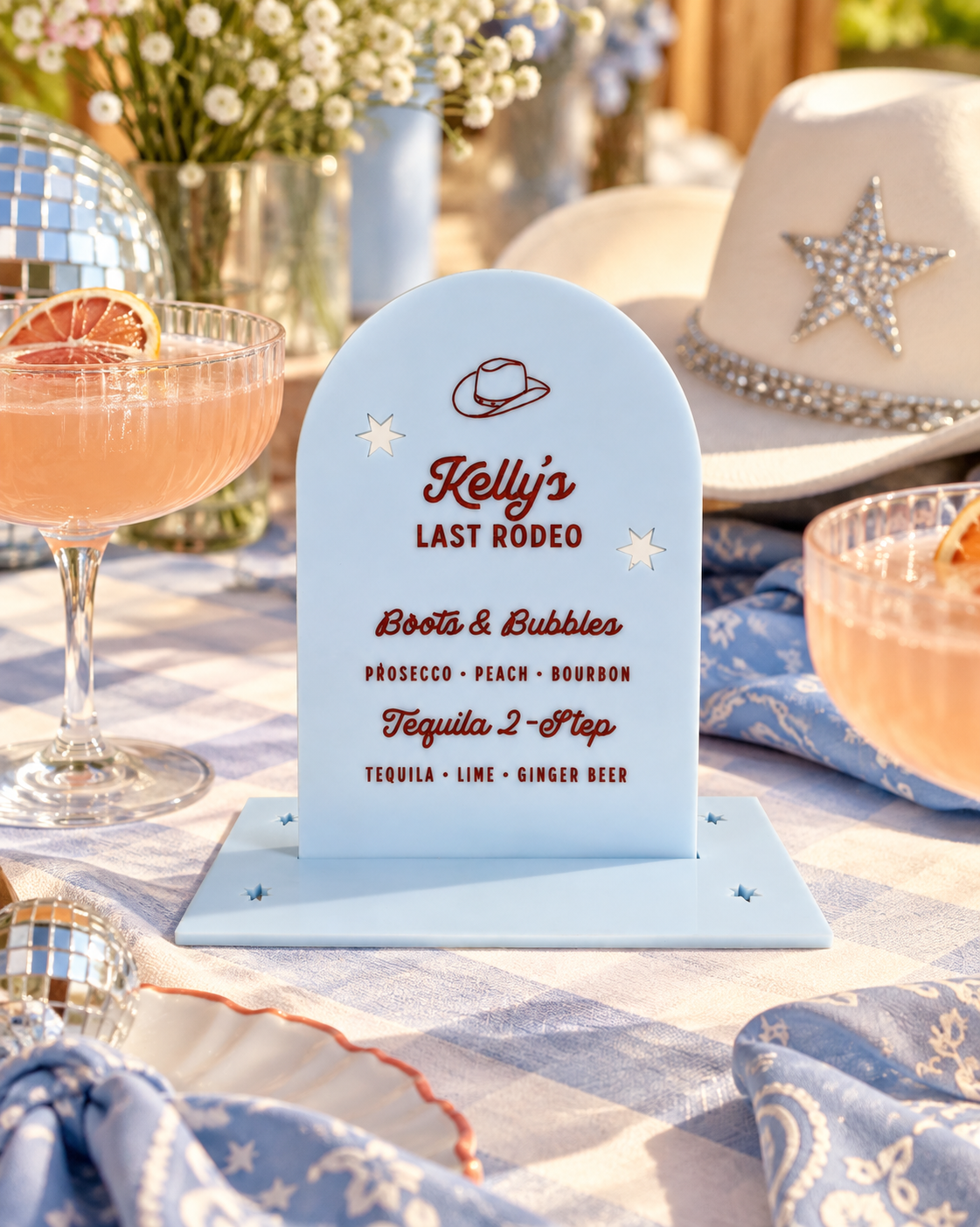 Personalized Last Rodeo signature drink sign on a styled western bachelorette table with cocktails and a cowboy hat